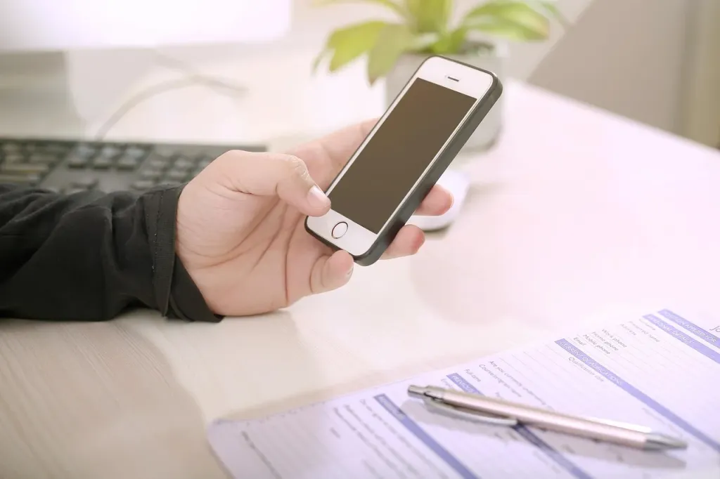 Dłoń trzymająca iPhone’a, prezentująca nowoczesny smartfon w codziennym użytkowaniu.