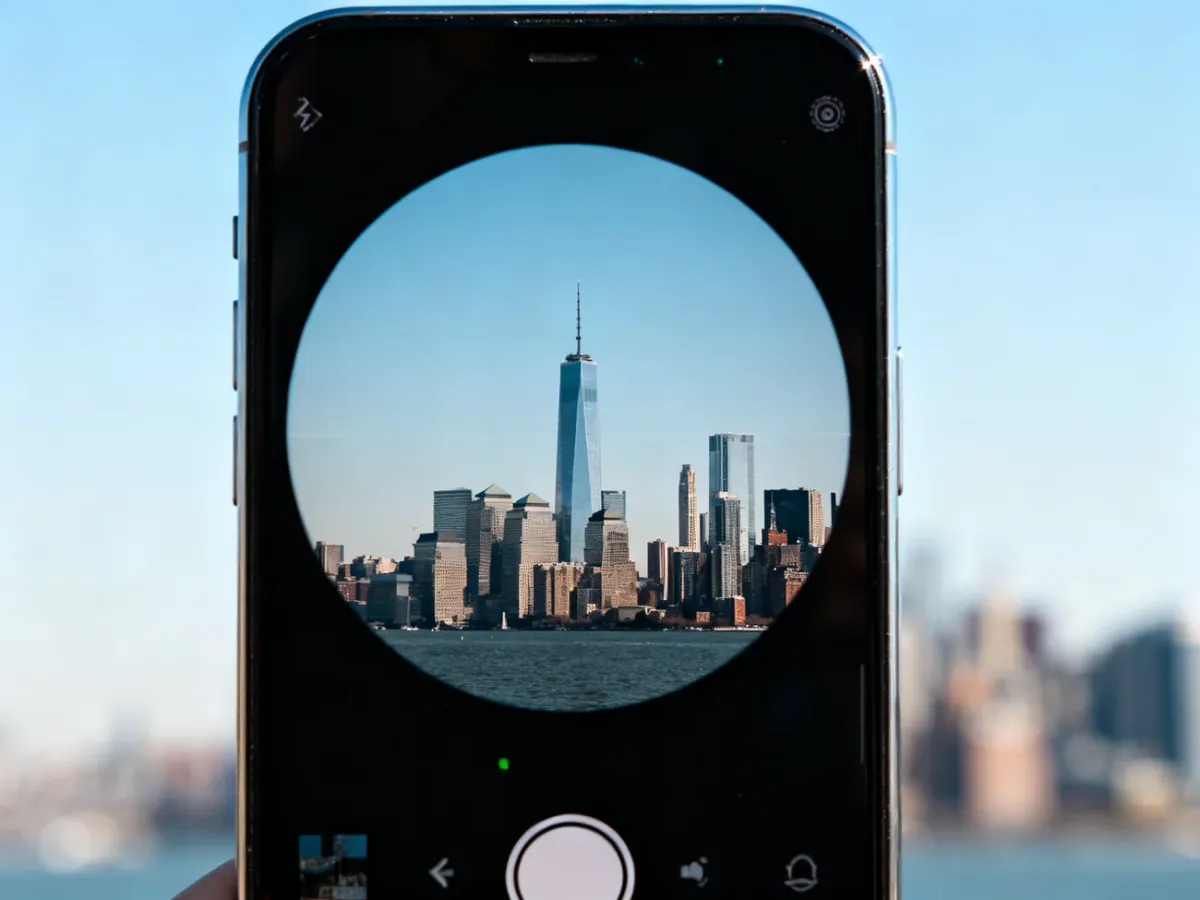 Smartfon fotografujący odległy miejski budynek przy użyciu teleobiektywu