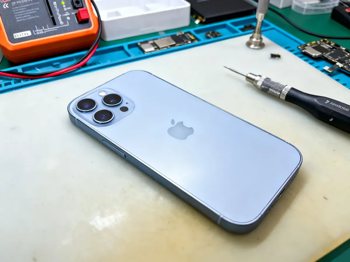 Refurbished iPhone 13 being inspected on a technician’s workbench