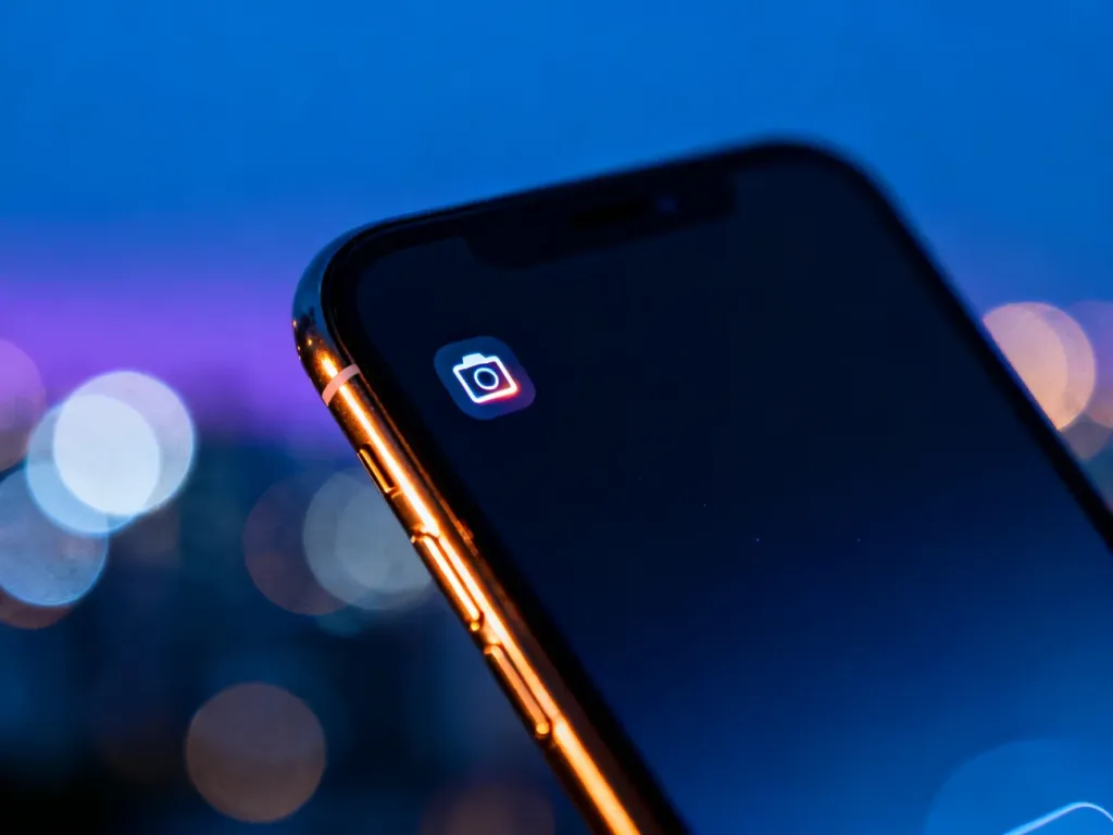 Smartfon z włączonym ciemnym motywem na tle rozmytego nocnego miasta, ilustrujący działanie trybu nocnego.